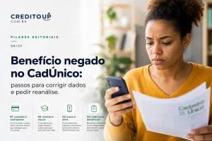 Mulher lendo documento e smartphone sobre benefício negado CadÚnico